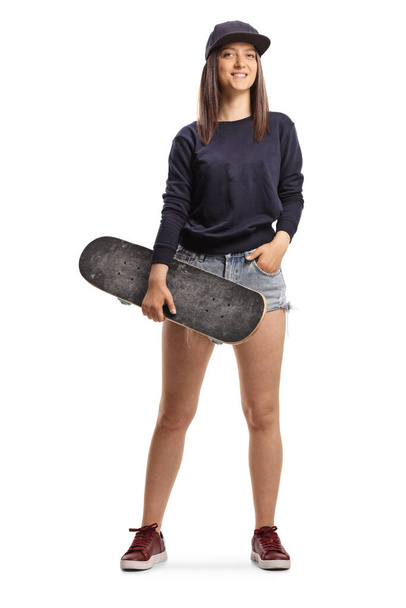 Full length portrait of a skater girl holding a skateboard isolated on white background - Photo, Image