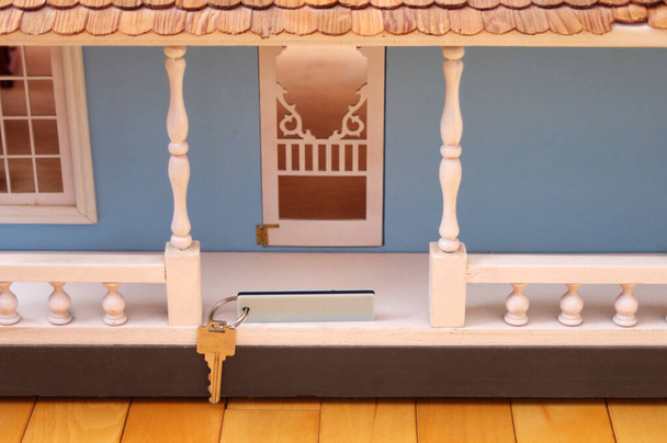 srebrny klucz z białym znaczkiem wiszącym przed dużym niebieskim drewnianym domkiem dla lalek  - Zdjęcie, obraz