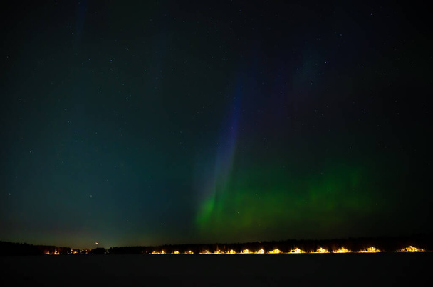Aurora boreal geomagnética de color verde en el cielo nocturno estrellado sobre una ciudad. Aurora Boreal sobre las islas lacustres suecas. Norte de Suecia. Cielo estrellado invernal. - Foto, Imagen