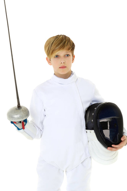 Boy in fencing costume posing with sabre and mask - 写真・画像