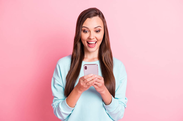 Photo of amazed pretty brown haired girl hold smartphone like reaction news isolated on pink color background - Fotoğraf, Görsel