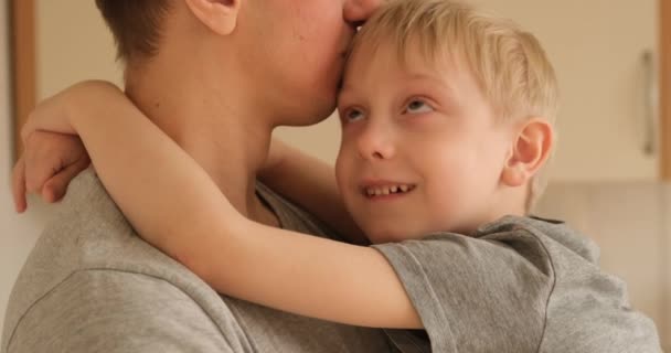 Boy tries to cheer up his frustrated father. Son sits in his arms and hugs his father. Home furnishings - Felvétel, videó
