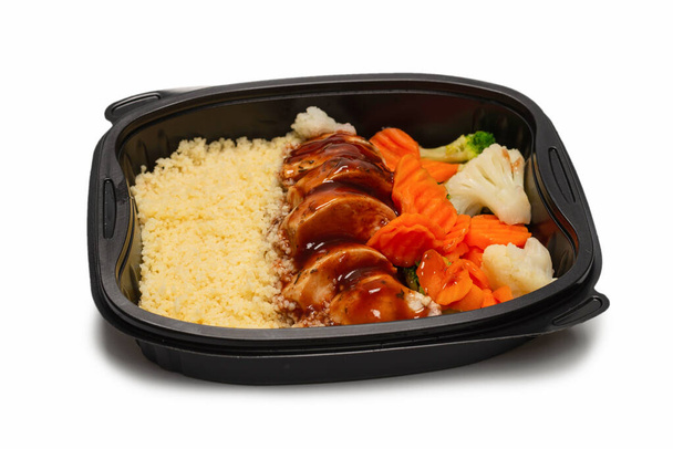 Ready food in a container. Stewed chicken in teriyaki sauce, stewed carrot, cabbage and porridge. Isolated on a white background.  - Foto, afbeelding