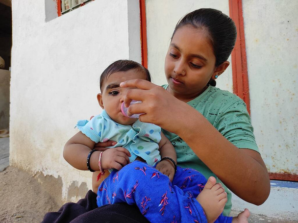 klein meisje geven zusje water uit flesje - Foto, afbeelding