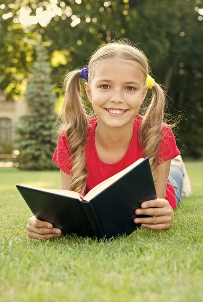 Small girl cute hairstyle reading book relaxing nature background, smart schoolgirl concept - Photo, Image