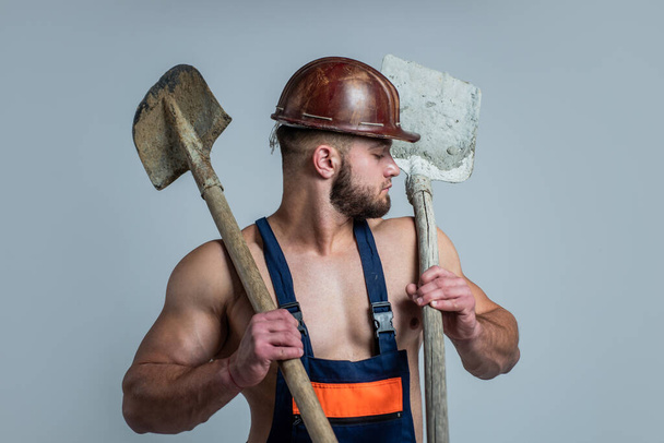 build and construction. sexy man with shovel. professional constructor or mechanic. builder engineer. muscular man architect with strong body. guy wear worker uniform. athletic builder in helmet - Фото, изображение