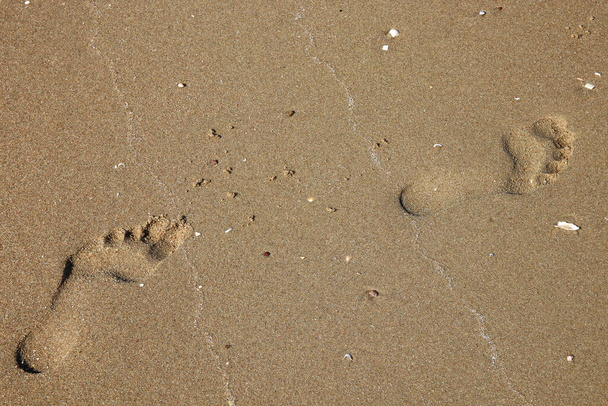 Huellas izquierda y derecha caminando en la arena en la playa - Foto, Imagen
