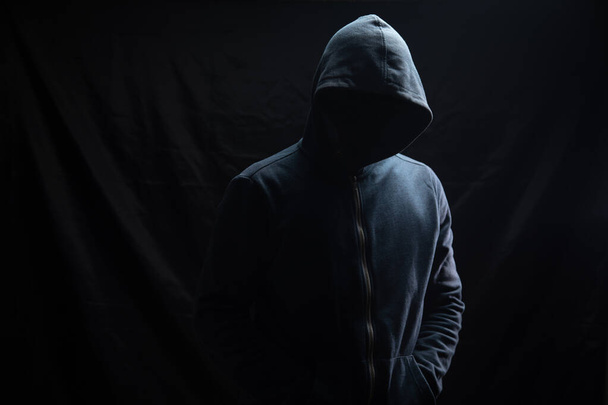 a man in a hood stands on a black background - Foto, Imagem