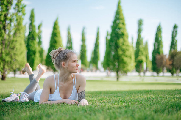 Attractive fille sportive se trouve sur l'herbe et se détend dans le parc - Photo, image