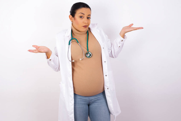 驚くほど手がかりのない妊娠中の医師の女性が腕を振って肩をすくめてこう言いました"誰が気にかけているのか,何が分からない"。 否定的な人間の感情. - 写真・画像