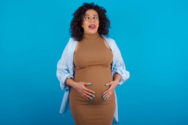 pregnant woman showing grimace face crossing eyes and showing tongue. Being funny and crazy - Photo, Image