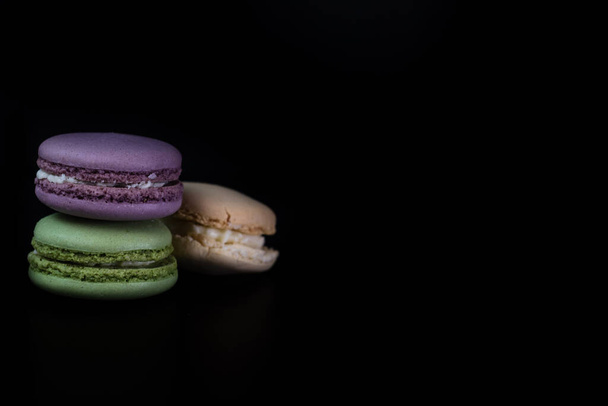 Bunte leckere Macarons isoliert auf schwarzem Hintergrund, Französisch Macarons Dessert - Foto, Bild