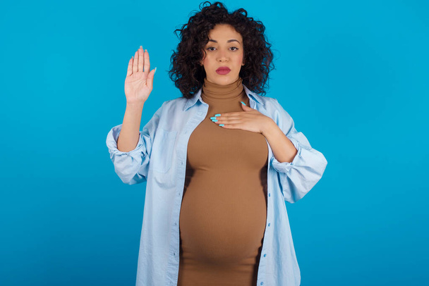 Hamile bir kadın, elleri göğsünde ve avuçları açık yemin ederek sadakat yemini ediyor. - Fotoğraf, Görsel