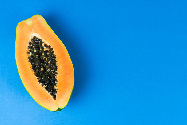 Half papaya on blue background. Copy space. Top view. - Photo, Image