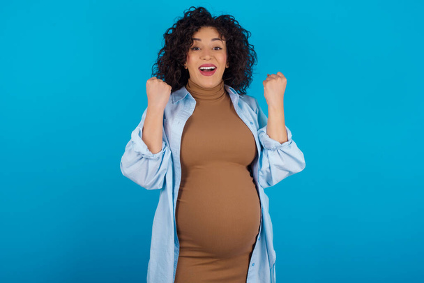 pregnant woman celebrating surprised and amazed for success with arms raised and open eyes. Winner concept. - Foto, afbeelding