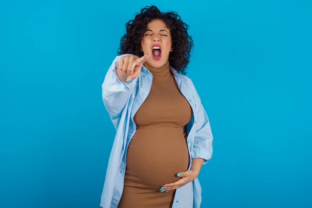 έγκυος γυναίκα δείχνει δυσαρεστημένη και απογοητευμένη στην κάμερα, θυμωμένη και έξαλλη έτοιμη να παλέψει μαζί σου.. - Φωτογραφία, εικόνα