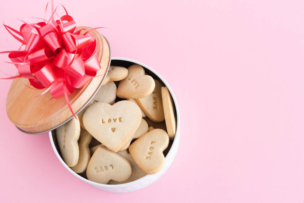 Caja con galletas en forma de corazón con decoraciones sobre fondo rosa. Copiar espacio. - Foto, imagen
