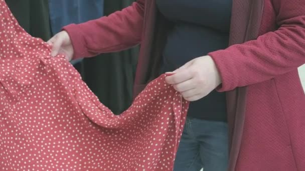 Zwangere vrouw in de winkel kiest voor ruime rode jurk met witte stippen kopen - Video