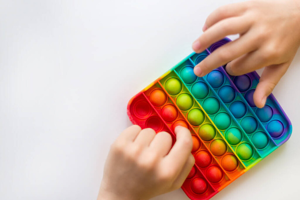 colorido antiestrés juguete sensorial fidget empuje pop en las manos de los niños. - Foto, Imagen