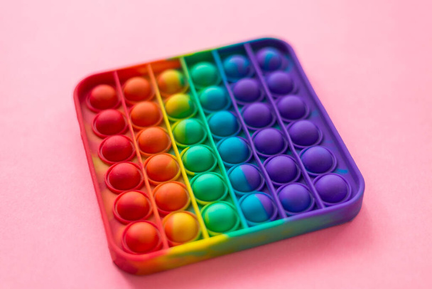 Anti-Stress ist ein Spielzeug. Rainbow touch Fidget Spinner, auf rosa Hintergrund. Neues Silikonspielzeug in Mode.. - Foto, Bild