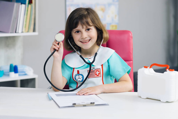Cute adorable little preschool kid girl smiling in hospital. Portrait shot of Female medical nurse in medic uniform looking at camera and smile - Foto, immagini