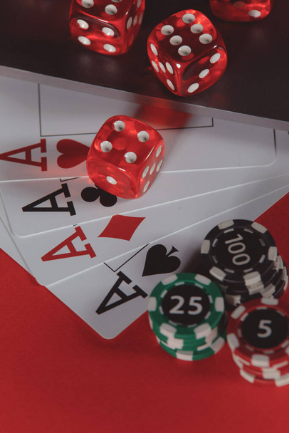 Red playing dice, chips and cards with aces on a red background. Poker online concept. Vertical image - Photo, Image