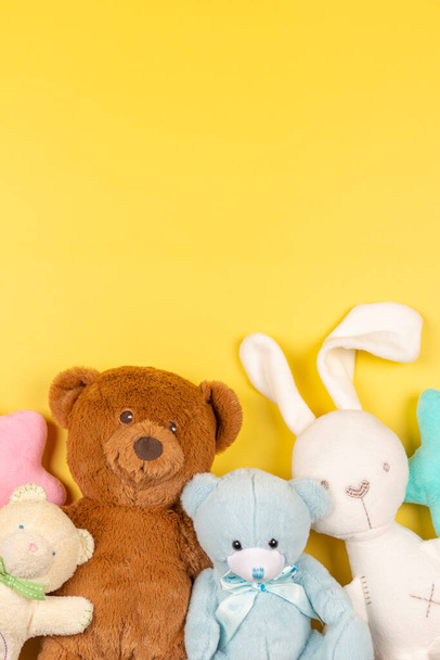 Fluffy toys teddy bears and white bunny on yellow background. Top view - Photo, Image