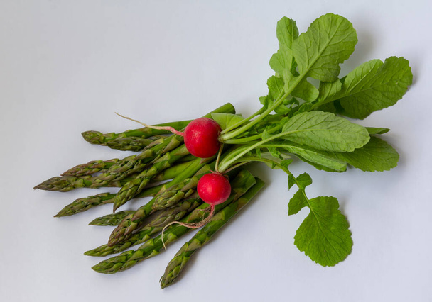 Espárragos verdes y rábanos rojos izolados en el espacio de copia de fondo blanco. Alimentos saludables, vitaminas - Foto, imagen