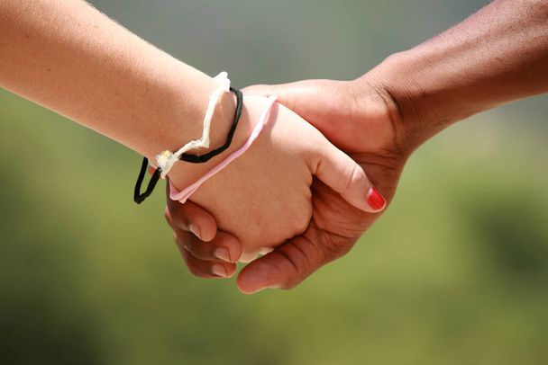 blank meisje en zwart jongen vasthouden handen - Foto, afbeelding