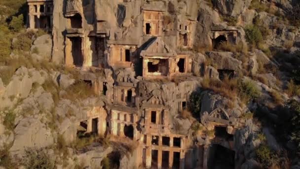 Ősi sírok kősziklába vésve Demre-ben. Aerial Drone Shot ókori görög szikla vágott lykian birodalom amfiteátrum és sírok Myra, Demre, Törökország - Felvétel, videó