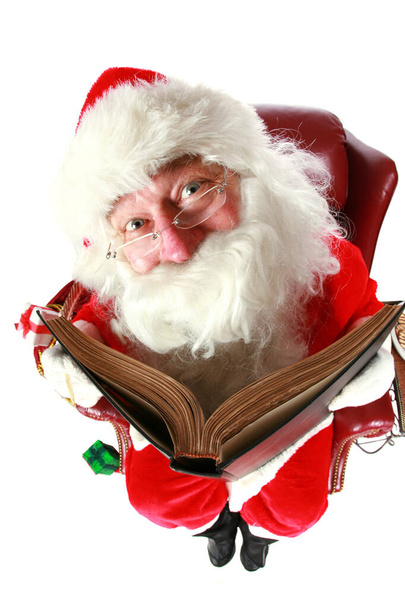 Święty Mikołaj sprawdza, kto był niegrzeczny lub miły w jego wielkiej książce. strzał z obiektywu rybie oko dla zabawy uroczyste wydarzenie. izolowany na biało z miejscem na tekst - Zdjęcie, obraz