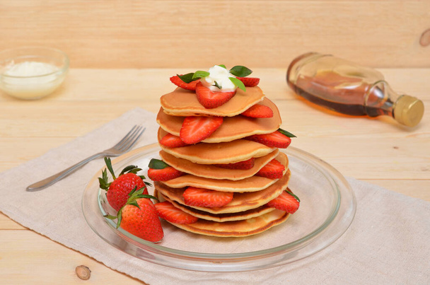 pancakes with strawberries and cream and maple syrup for them on the table - Zdjęcie, obraz