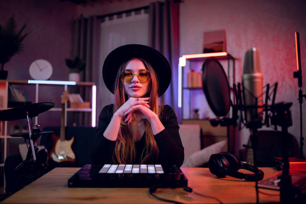 Female musician sitting at table with modern instruments - Foto, Imagen