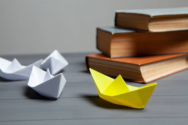 white boats go for yellow next to books on a gray background - Foto, imagen