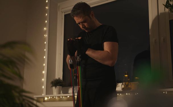 Mann macht zu Hause Übungen mit Widerstandsbändern. - Foto, Bild