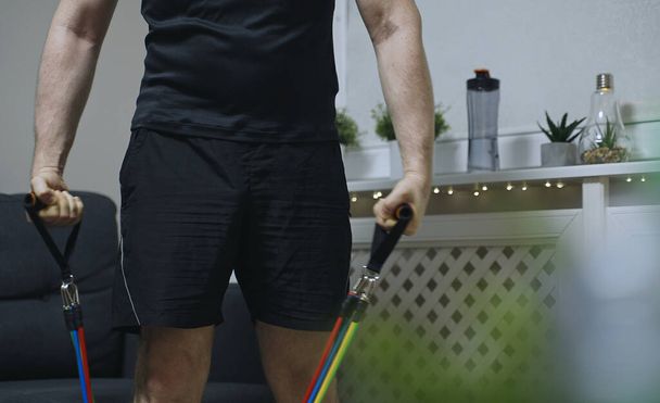 Mann macht zu Hause Übungen mit Widerstandsbändern. - Foto, Bild