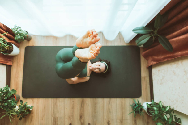 Frau macht Yoga zu Hause in der Nähe großen Fensters gesunden Lebensstil - Foto, Bild