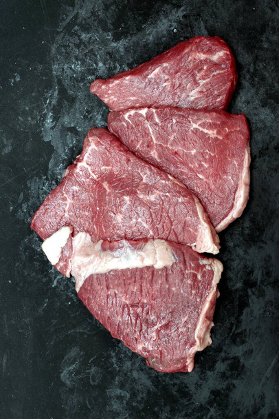 Különféle nyers steakek. Sirloin marhahús steak, felülnézet. Sok nyers Striploin Steak a márvány marhahús fekete háttér. Fekete Angus marhahús csoport. Nyers Sirloin vágás. Főzés nélküli Prime Beef Steak. - Fotó, kép