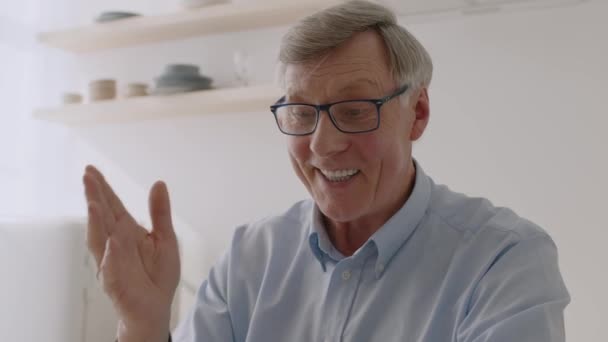 Cheerful senior grand-père vidéo bavarder avec la famille, saluer la main et parler avec des parents à la cuisine, pistage tourné - Séquence, vidéo