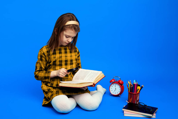 Slimme kleine kind met vergrootglas om boek te lezen tijdens de studies - Foto, afbeelding