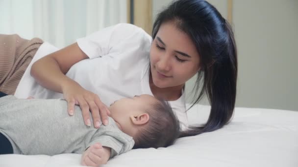 Detailní mladý asijské matka políbit malé dítě dívka se spánkem a nevinností na posteli v ložnici doma, maminka péče o novorozence a sbližování, žena pocit štěstí s dcerou, rodina a životní styl koncept. - Záběry, video