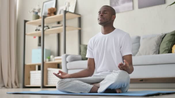 Hombre africano pacífico meditando en la esterilla de yoga en casa - Metraje, vídeo