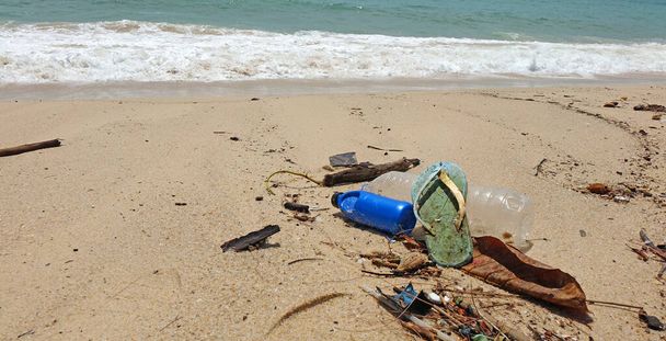 Verschmutzung am Strand. Plastikflaschen, Plastikmüll und Schuhe im Meer. Weltumwelttag, Umweltschutzkonzepte. Selektiver Fokus - Foto, Bild