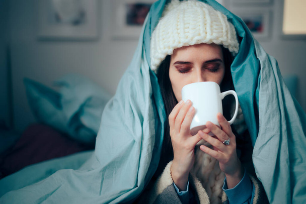Mujer sintiendo frío en casa bebiendo bebidas calientes - Foto, Imagen