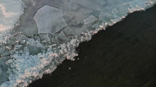 Vista aerea del lago ghiacciato. Acqua scura parzialmente ricoperta di ghiaccio e grandi pezzi di ghiaccio - Foto, immagini