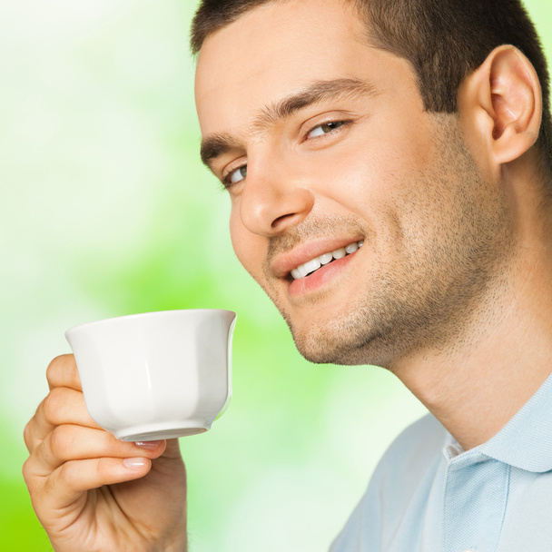 Young smiling man with cup of coffee, outdoors - Foto, Bild