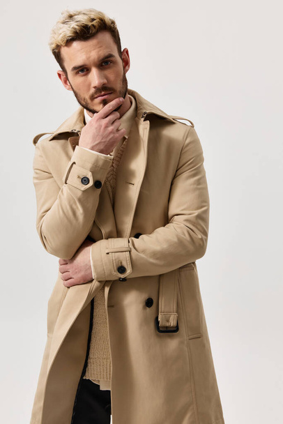 pensive blond man in beige coat holds hand near face portrait - Photo, image