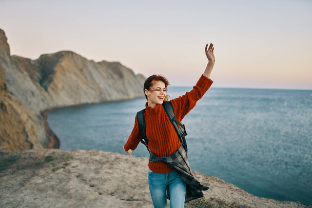 nainen turisti elehtii kädet vuorilla lähellä merta luonnossa ylhäältä - Valokuva, kuva