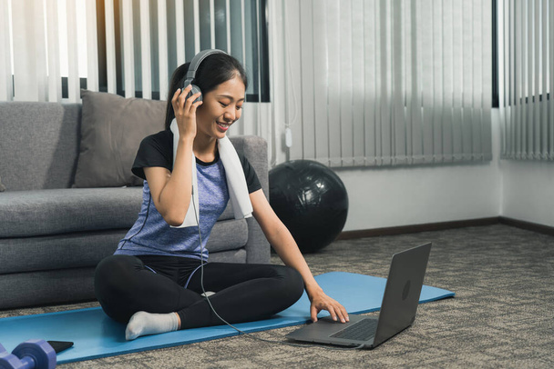 Asian beautiful young woman using laptop and headphones listen music while practicing exercise yoga at home. - Photo, Image