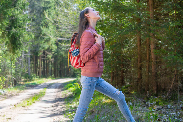 Pretty one teen young tourist girl relaxing on forests road.Teenage with backpack on green forest summer or spring. - Foto, Imagen